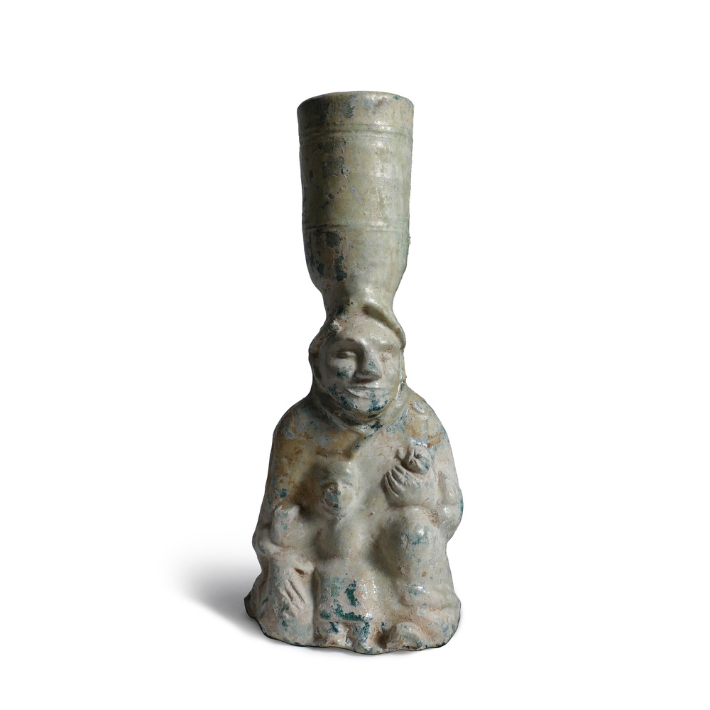 A green-glazed pottery figural candle holder